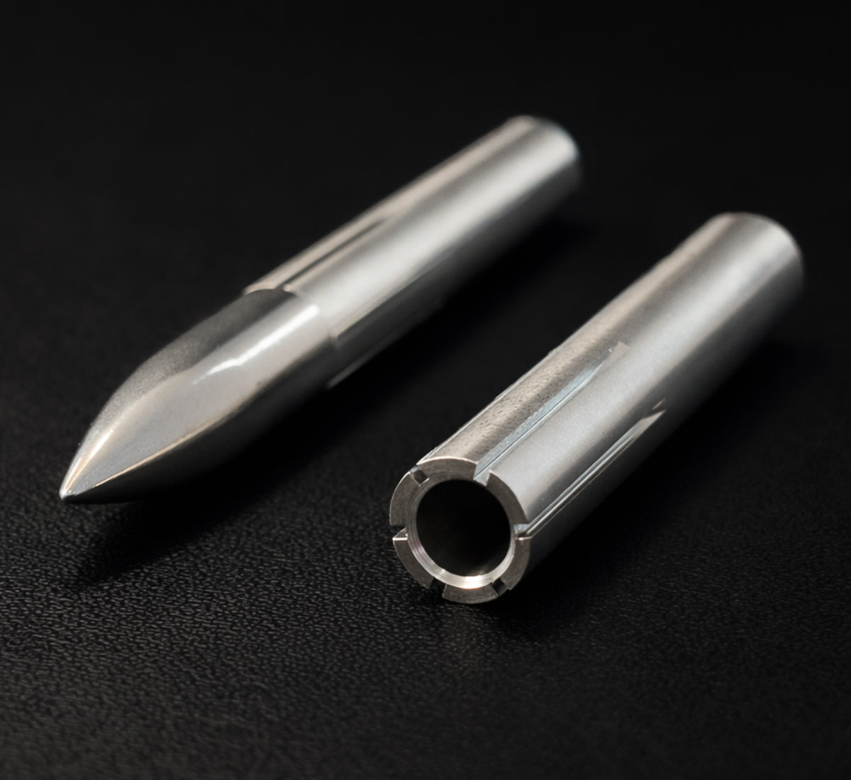 Two metal cylindrical objects on a black background